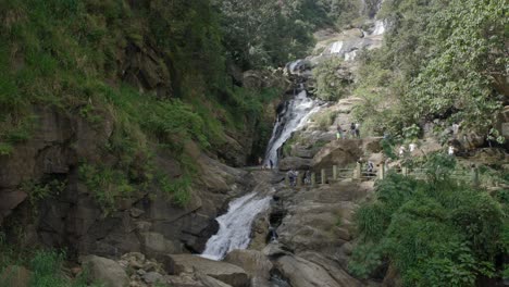 Unrecognizable-tourists-enjoying-beautiful-Ravana-Falls,-Sri-Lanka
