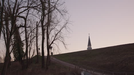 European-bell-tower-behind-hill-and-tree-in-the-foreground
