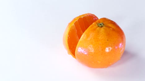 Very-sharp-knife-cutting-a-thic-slice-of-tangerine-in-white-surface