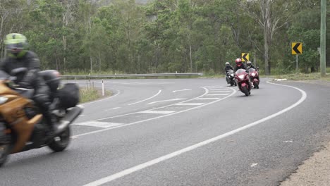 Group-of-motorcyclists-ride-around-a-bitumen-corner-and-pass-camera