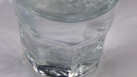 Makroaufnahme-Des-Gießens-Von-Wasser-In-Ein-Glas-Und-Überlaufen-Mit-Weißem,-Sauberem-Und-Klarem-Hintergrund