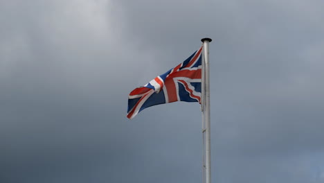 Ondeando-La-Bandera-Británica-Union-Jack-Del-Reino-Unido-Ondeando-En-Un-Viento-Fuerte