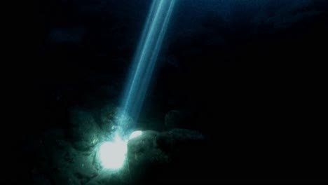 Explorando-El-Agua-Oscura-De-Una-Cueva-Marina-Con-Un-Haz-Natural-De-Luz-Solar-Iluminando-Rocas-Bajo-El-Agua-En-Una-Atmósfera-Misteriosa,-Isla-De-Vis,-Mar-Adriático,-Croacia