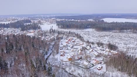 Flying-Over-Village-Among-Snowbound-Woodlands-And-Glades-In-Winter