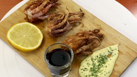 Adding-pepper-to-a-wood-table-with-fried-squid,-soy-sauce,-lemon-and-aioli