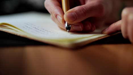 Caucasian-right-hand-holding-modern-ink-pen-writing-new-idea-on-paper-notebook-journal