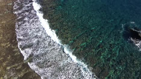 Flying-over-seashore-with-waves-breaking-on-uniquely-shaped-stone-reefs