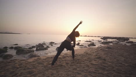Black-afro-woman-practicing-yoga-at-sunrise-on-sandy-beach,-mindfulness-meditative-asana-poses-workout-for-healthy-morning-routine