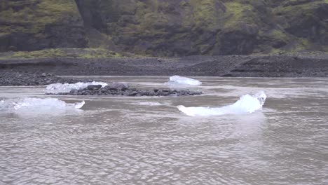 Témpanos-De-Hielo-En-Un-Río-Rápido-Con-Costas-Volcánicas-Negras-En-Islandia