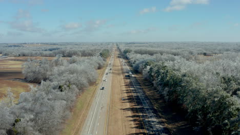 Aerial-drone-moving-down-long-rural-interstate-highway-road-in-winter,-4K