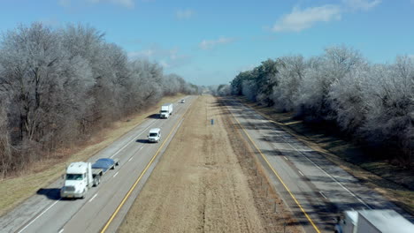 Static-aerial-view-over-rural-interstate-highway-road-as-trucks-pass,-4K