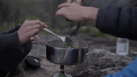 Cooking-on-a-camping-trip-in-the-mountains,-food-is-steaming-and-seasoning