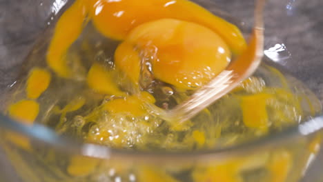 Mixing-Eggs-with-a-Fork,-Making-Scrambled-Eggs-in-a-Glass-Bowl,-Mixing-Egg-Yolk-and-White