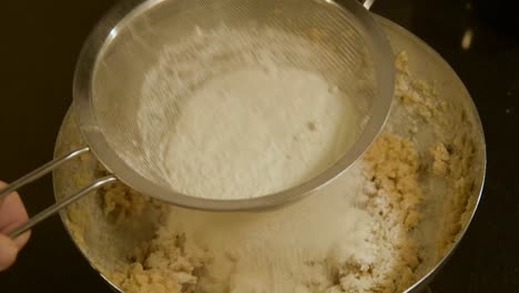 mixing-flour-through-a-sieve