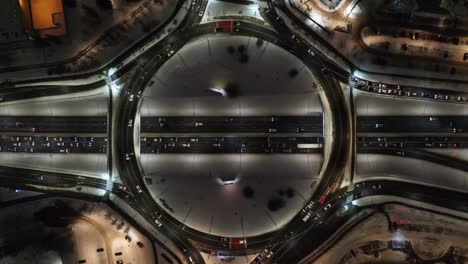Aerial-View-Above-Traffic-at-a-Roundabout-on-a-Late-Winter-Evening-During-Rush-Hour