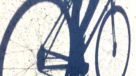 Shadow-of-a-man-cycling-along-a-dirt-track-in-bright-sunshine