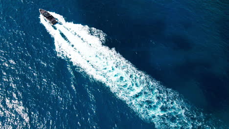 Luxury-speedboat-travelling-across-frame-in-clear-glistening-Mediterranean-Sea-in-Mallorca-aerial-top-down-view