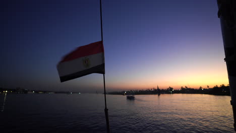 Die-ägyptische-Flagge-Weht-Bei-Sonnenuntergang-Auf-Einem-Segelboot,-Während-Sie-Auf-Dem-Berühmten-Nilo-Kreuzen