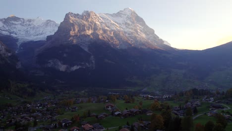 aerial-drone-footage-pushing-in-over-Grindelwald-village,-stunning-view-of-Eiger-North-Face-at-sunset