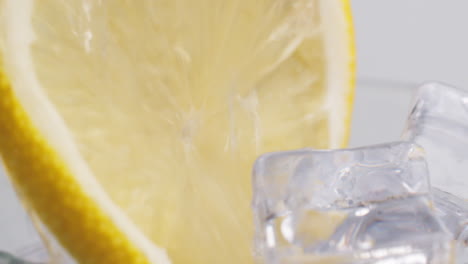 Cold-fresh-sparkling-water-poured-into-a-glass-with-ice-and-lemon-slices