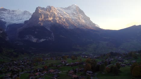 aerial-drone-footage-pushing-out-over-Grindelwald-village,-sunset-view-of-Mount-Eiger