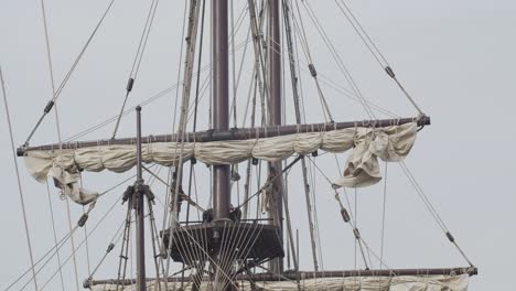 Galleon-Andalucia-replica-ship-with-spanish-flag-detail-tilt-shot-of-masts-and-sails-while-docked-in-Valencia-in-slow-motion-60fps
