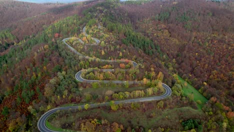 Aerial-video-of-a-winding-mountain-road-surrounded-by-a-forest-with-autumn-trees-in-the-Bieszczady-Mountains-in-Poland,-Europe