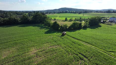 An-aerial-view-of-an-agricultural-crop-sprayer-driving-on-a-field-lane-in-the-farmland-of-Lancaster-County,-Pennsylvania