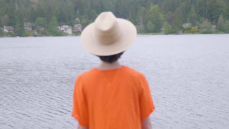 Woman-in-Vibrant-Orange-Dress-Walking-out-the-the-Lake,-Rear-Shot