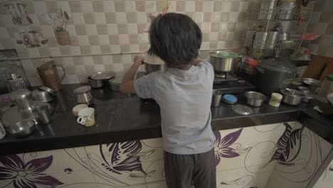 Handheld-shot-of-little-Asian-girl-boiling-milk-in-the-kitchen,-from-the-back-and-side-angle
