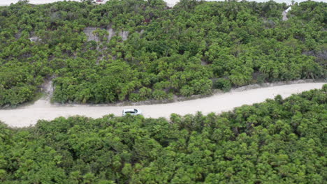 SUV-driving-on-a-peninsula-traveling-through-green-Tulum-Mexico-rotating-shot