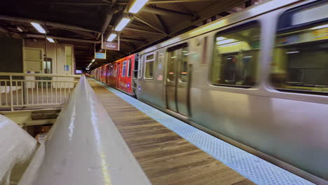 Silver-subway-train-comes-to-a-stop-at-an-empty-station-at-night