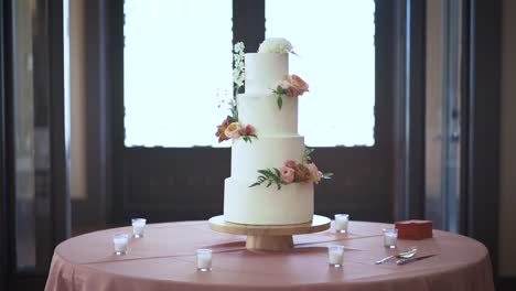 A-wedding-cake-sits-on-a-table-complete-with-decor-and-the-camera-slowly-comes-in-on-the-sweet-tower-of-baked-bliss
