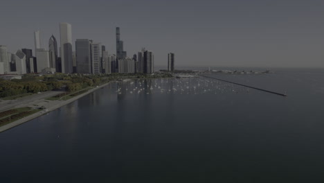 Aerial-drone-footage-rising-up-and-revealing-Chicago,-Illinois-skyline-and-Lake-Michigan,-Grant-Park,-Millennium-Park,Monroe-Harbor,-and-Navy-Pier-at-sunrise-in-the-October-fall