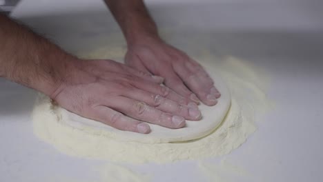 Slow-motion-close-up-of-spreading-out-pizza-dough-by-hand