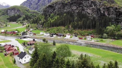 Aerial:-flying-over-the-Flåm-valley-among-mountains,-houses,-rivers-and-green-meadows
