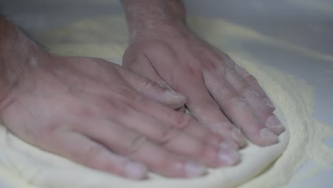Slow-motion-close-up-of-laying-out-pizza-dough-by-hand