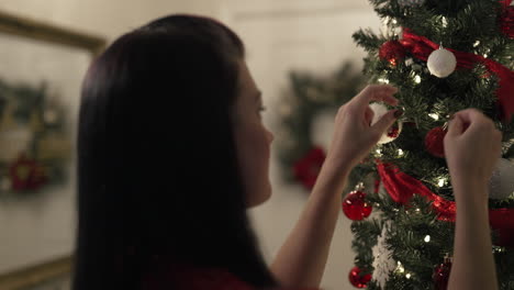 Over-the-shoulder-shot-of-woman-decorating-beautiful-Christmas-tree