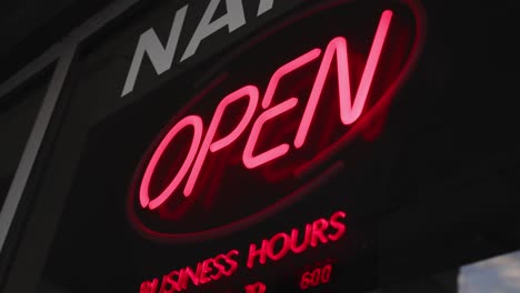 An-unlit-open-business-sign-stands-still-when-a-hand-from-inside-reaches-to-the-sign-and-turns-it-on
