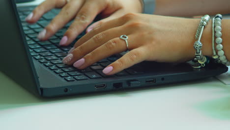 Woman's-hand-with-pink-polished-nails,-typing-fast-on-laptop-keyboard