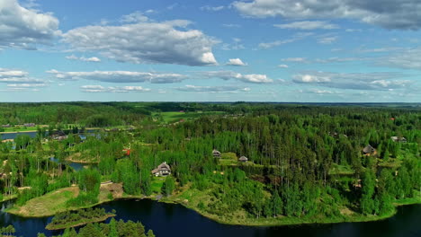 slowly-flying-backwards-drone-flight-over-a-beautiful-colorful-forest-landscape-with-houses-on-a-lake-is-like-a-fairytale-view