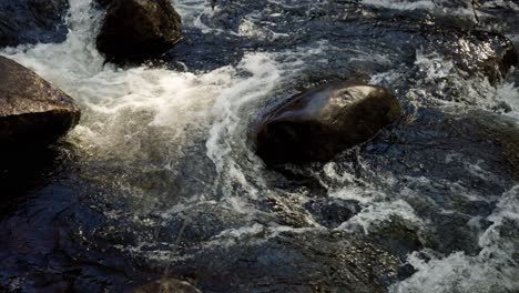 Closeup-Of-Moving-Water-Through-River-Rocks