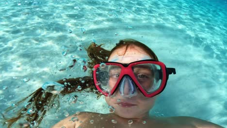 Unterwasser-Selfie-Eines-Jungen-Mädchens-Mit-Roten-Haaren-Und-Einer-Tauchermaske,-Die-Eine-Kamera-Hält,-Während-Sie-Spaß-Im-Kristallklaren-Türkisfarbenen-Meerwasser-Hat
