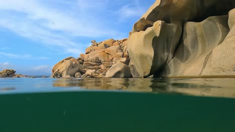 Halber-Unterwasserschwenkblick-Auf-Große-Felsen-Aus-Rosa-Granit-In-Der-Bucht-Cala-Della-Chiesa-Auf-Der-Berühmten-Französischen-Insel-Lavezzi-Zwischen-Korsika-Und-Sardinien,-Frankreich