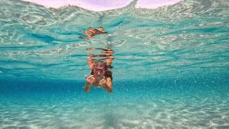 Underwater-scene-of-young-redhead-girl-swimming-undersea-in-crystal-clear-turquoise-tropical-sea-water-of-exotic-island