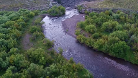 Drone-view-of-a-small-river-transforming-in-a-waterfall-on-top-of-a-creek