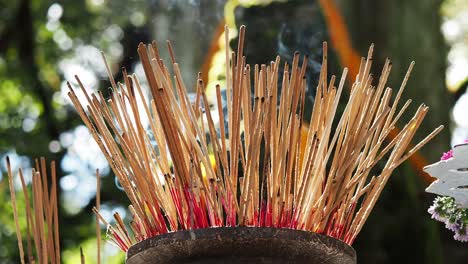 Burning-incense-sticks-and-smoke-in-sunlight-with-lip-of-pot