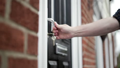 Unlocking-black-front-door-with-house-keys-mans-hand