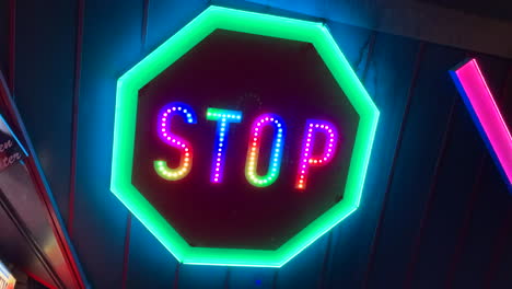 Neon-illuminated-STOP-sign-glowing-in-many-different-colors