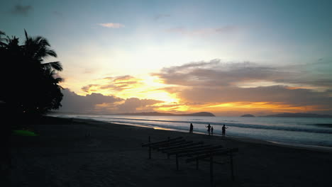 Zeitlupe-Von-Silhouetten,-Die-Den-Strand-Auf-Den-Philippinen-Hinuntergehen,-Und-Der-Sonnenuntergang-Ist-Im-Hintergrund